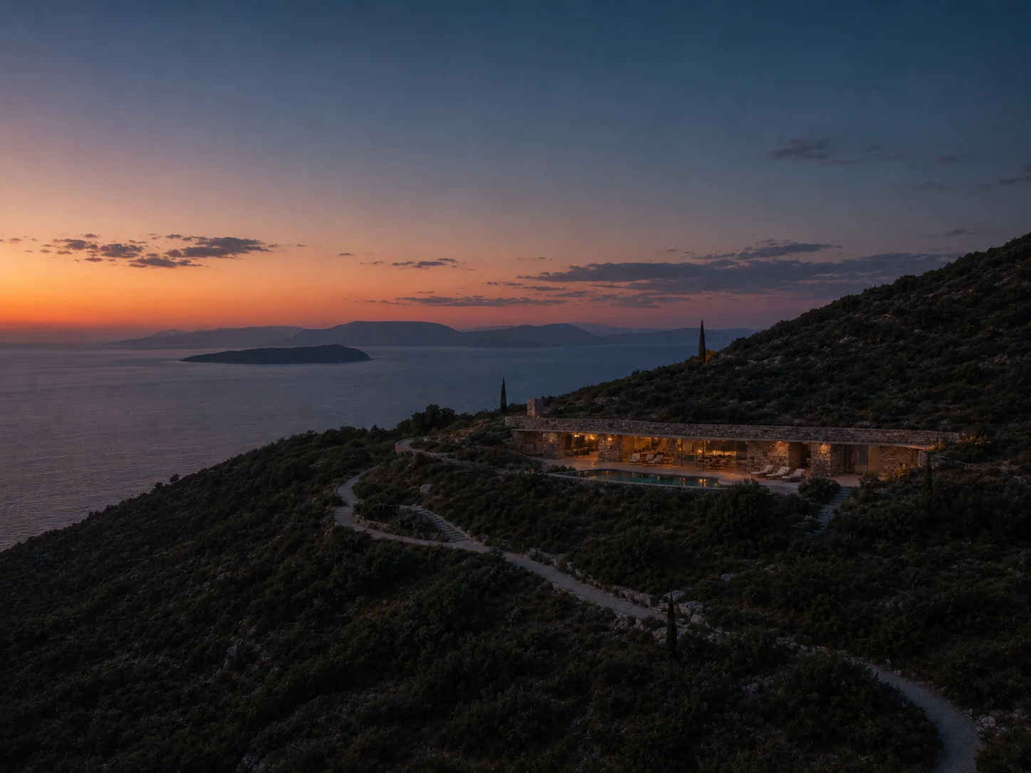 A low stone residence embedded in a Lefkada hillside at dusk overlooking the Ionian Sea